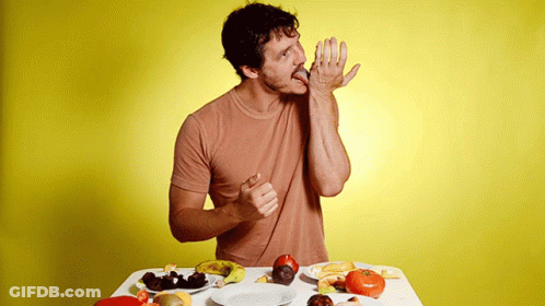 A Man Is Sitting At A Table With A Plate Of Food GIF