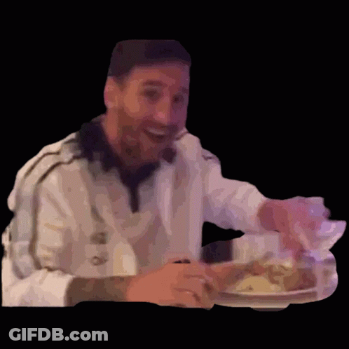 A Man Is Sitting At A Table With A Plate Of Food In His Hand . GIF