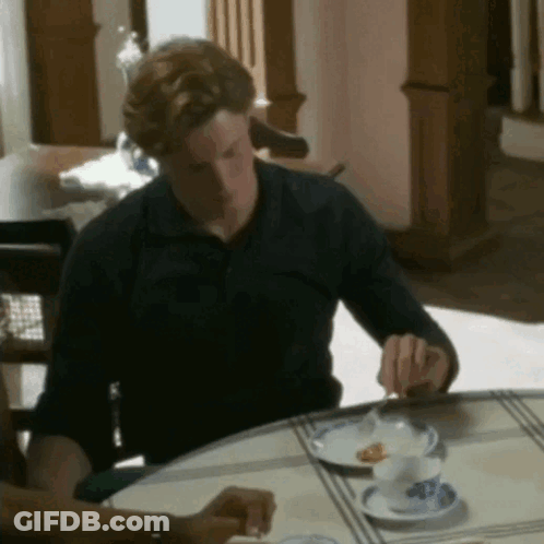 A Man Is Sitting At A Table With A Plate Of Food On It GIF