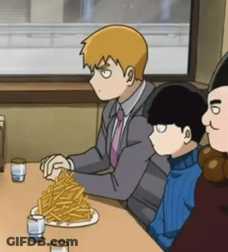 A Man Is Sitting At A Table With A Plate Of French Fries . GIF