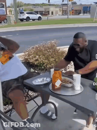 A Man Is Sitting At A Table With A Tray Of Food On It GIF