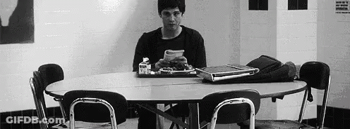 A Man Is Sitting At A Table With A Tray Of Food . GIF
