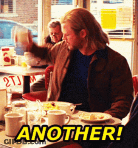 A Man Is Sitting At A Table With Another Written On The Table GIF