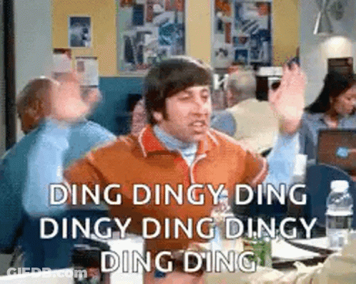 Man Sitting At Table With Hands In Air Saying Ding Dingy GIF