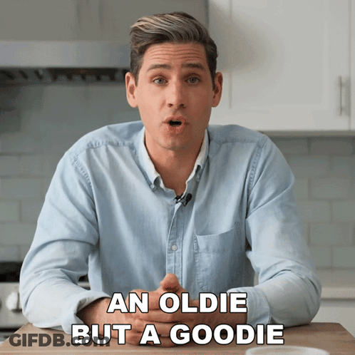 A Man Is Sitting At A Table With The Words An Oldie But A Goodie Behind Him GIF