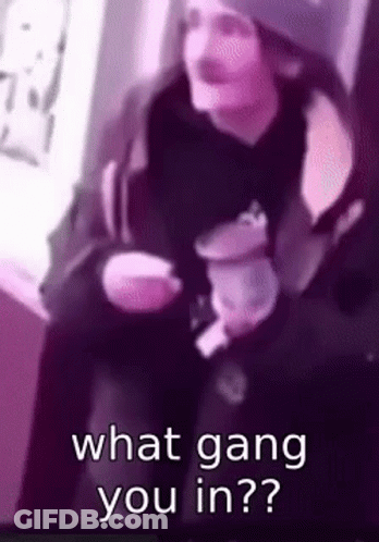 A Man Is Sitting Down Holding A Cup Of Coffee And Asking What Gang You Are In . GIF