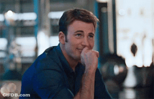 A Man Is Sitting Down With His Hand On His Chin And Smiling . GIF