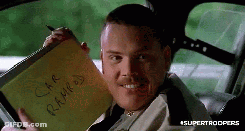 A Man Is Sitting In A Car Holding A Notepad That Says `` Car Ramped '' On It . GIF