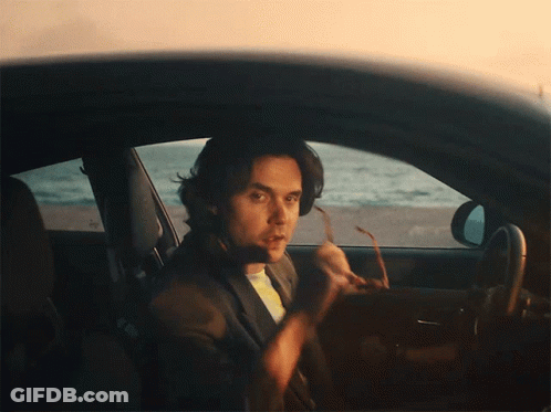 A Man Is Sitting In A Car Holding A Pair Of Sunglasses GIF