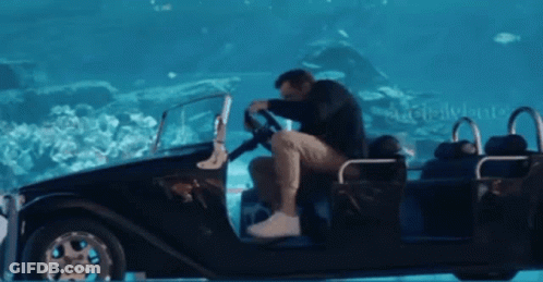 A Man Is Sitting In A Car That Is Floating In The Water With The Word Disneyland In The Background GIF
