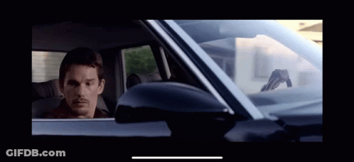 A Man Is Sitting In A Car With A Gun On The Windshield GIF