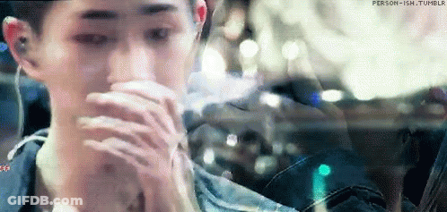 A Man Is Sitting In A Car With His Hands On His Face And Looking Out The Window . GIF