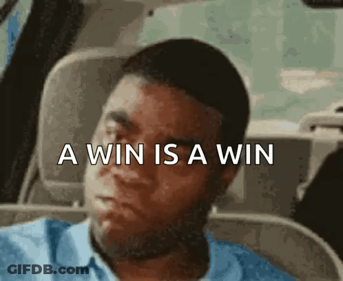 A Man Is Sitting In A Car With The Words A Win Is A Win Written Above Him . GIF