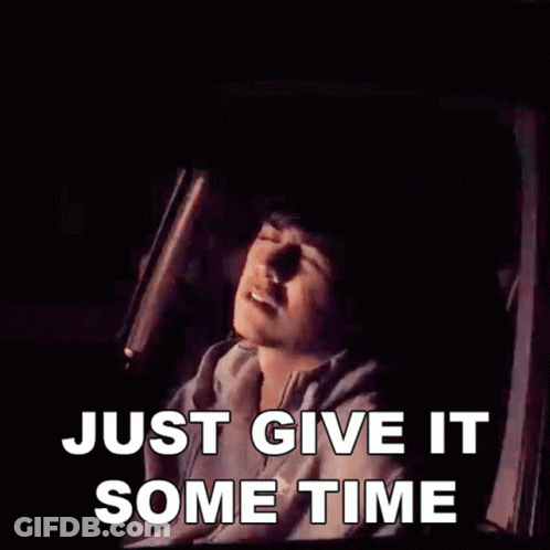 A Man Is Sitting In A Car With The Words Just Give It Some Time Above Him GIF