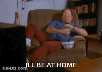 A Man Is Sitting In A Chair Eating Popcorn And Drinking Beer While Watching Television . GIF