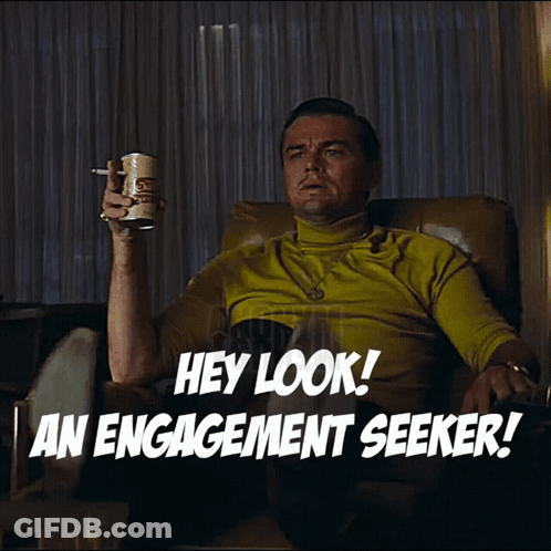 A Man Is Sitting In A Chair Holding A Can Of Beer And Pointing At Something With The Words Hey Look An Engagement Seeker GIF
