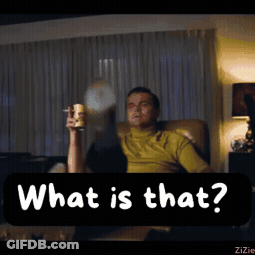 A Man Is Sitting In A Chair Holding A Glass And A Cigarette And The Words What Is That Are Above Him GIF