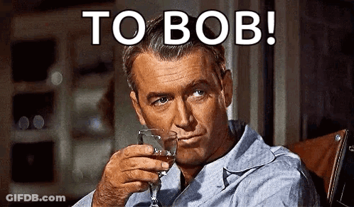 A Man Is Sitting In A Chair Holding A Glass Of Whiskey And Smoking A Cigarette . GIF