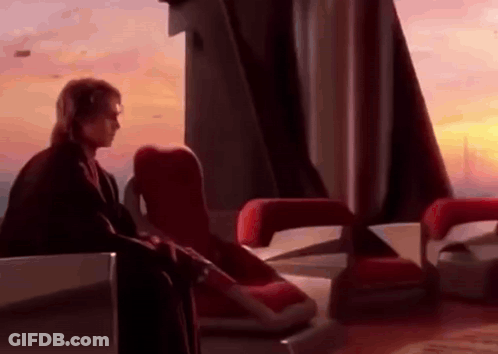 A Man Is Sitting In A Chair In Front Of A Window In A Room . GIF
