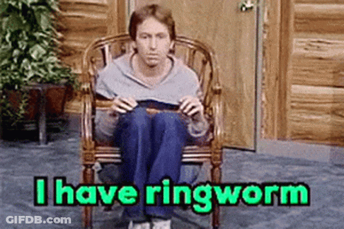 A Man Is Sitting In A Chair Reading A Book With The Words I Have Ringworm Above Him . GIF