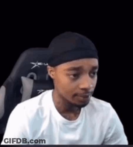 A Man Is Sitting In A Chair Wearing A Headband And A White Shirt . GIF