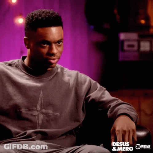 A Man Is Sitting In A Chair Wearing A Sweatshirt That Says " Desus & Mero " GIF
