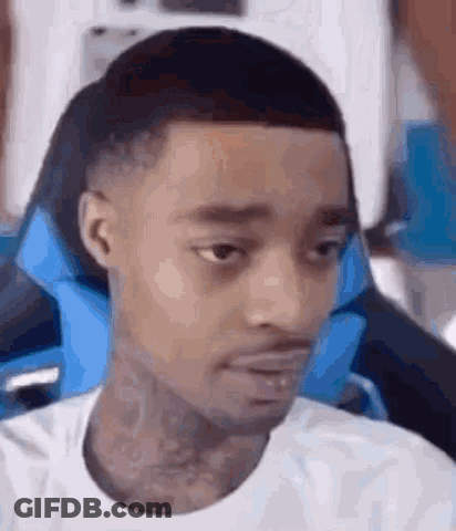A Man Is Sitting In A Chair With A Blue Pillow On His Head . GIF