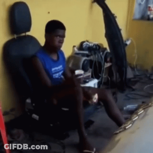 A Man Is Sitting In A Chair With A Coca Cola Bottle On The Wall Behind Him GIF