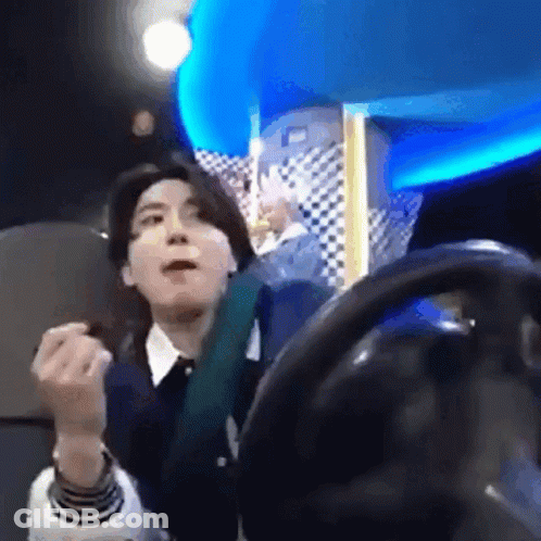 A Man Is Sitting In A Chair With A Steering Wheel In Front Of Him And Making A Funny Face . GIF