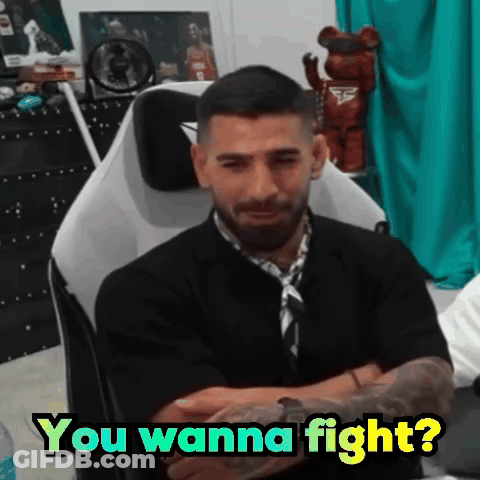 A Man Is Sitting In A Chair With His Arms Crossed And Says " You Wanna Fight ? " GIF