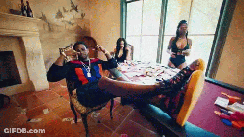 A Man Is Sitting In A Chair With His Feet Up And Two Women Are Sitting At A Table With Their Feet Up . GIF