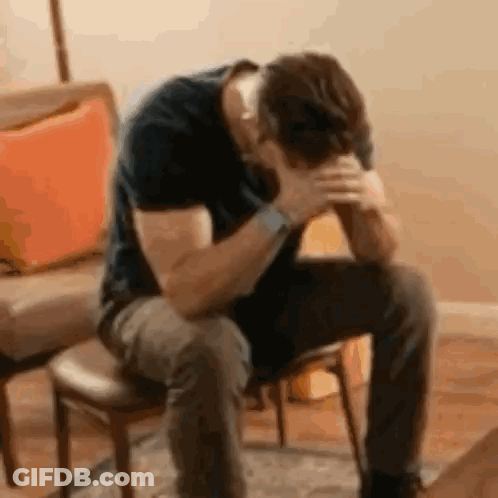 A Man Is Sitting In A Chair With His Hands On His Head . GIF