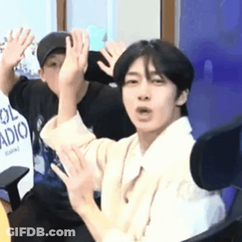 A Man Is Sitting In A Chair With His Hands Up . GIF