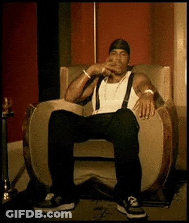A Man Is Sitting In A Chair With His Legs Crossed And Smoking A Cigarette . GIF