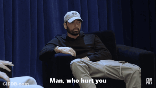 A Man Is Sitting In A Chair With The Words Man Who Hurt You Below Him GIF