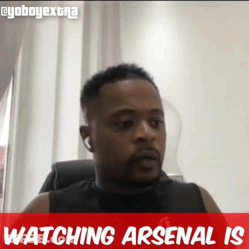 A Man Is Sitting In A Chair With The Words Watching Arsenal Is Behind Him GIF
