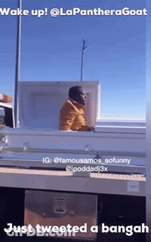 A Man Is Sitting In A Coffin On The Back Of A Truck .. GIF