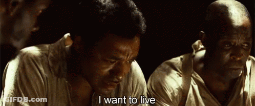 A Man Is Sitting In A Dark Room And Saying I Want To Live . GIF