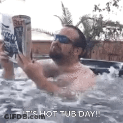 A Man Is Sitting In A Hot Tub Reading A Book While Holding A Can Of Beer . GIF