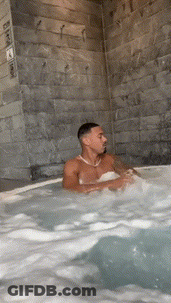 A Man Is Sitting In A Hot Tub With A Bikini On . GIF