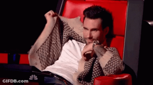 A Man Is Sitting In A Red Chair With His Arms Outstretched And A Watch On His Wrist . GIF