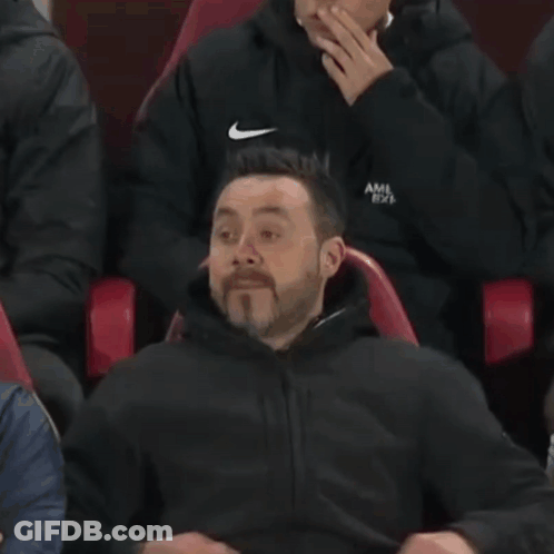 A Man Is Sitting In A Red Chair With His Face Covered . GIF