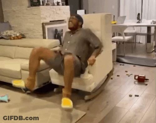 A Man Is Sitting In A Rocking Chair In A Living Room With A Couch . GIF
