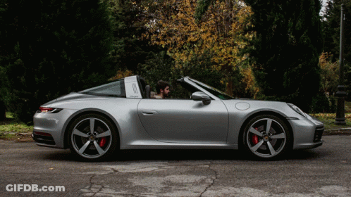 A Man Is Sitting In A Silver Porsche Targa GIF