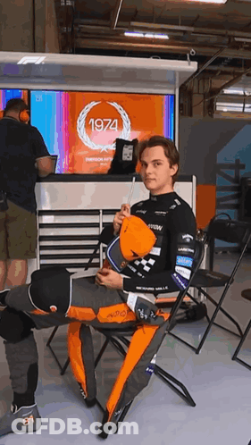 A Man Is Sitting In Front Of A 1974 Sign GIF