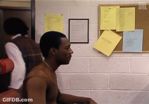 A Man Is Sitting In Front Of A Bulletin Board With A Snl Logo On It GIF