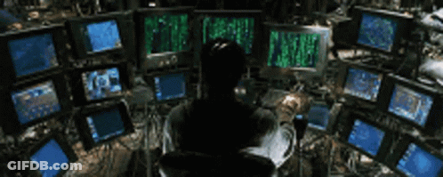 A Man Is Sitting In Front Of A Bunch Of Computer Monitors With The Word Matrix On The Screens GIF