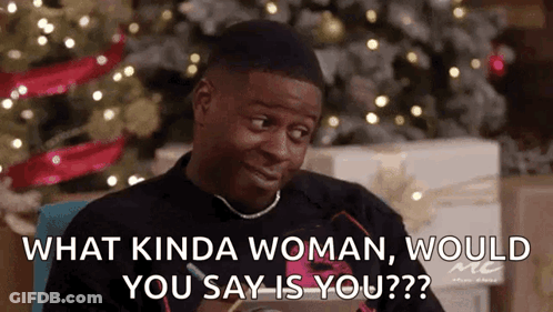 A Man Is Sitting In Front Of A Christmas Tree And Talking To Another Man . GIF