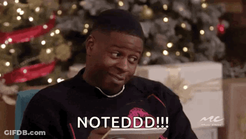 A Man Is Sitting In Front Of A Christmas Tree Holding A Tablet And Says Notedd . GIF