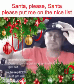 A Man Is Sitting In Front Of A Christmas Tree With A Person Putting A Hat On His Head . GIF